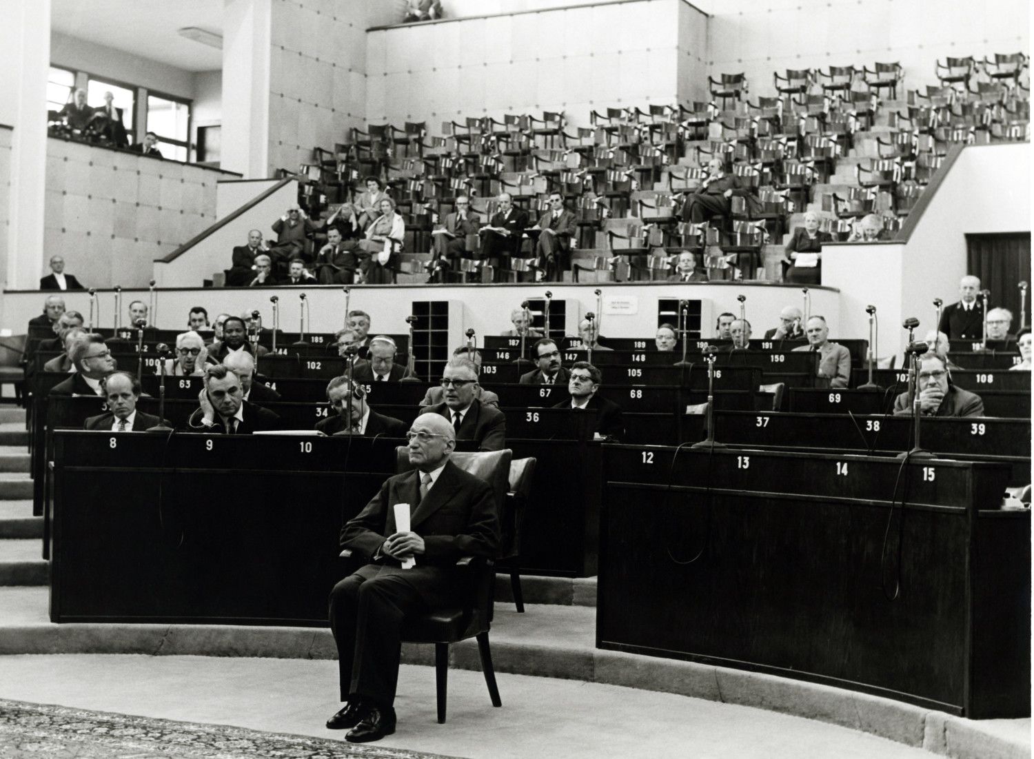 Robert Schuman sedí uprostřed sálu při plenárním zasedání v Evropském parlamentu.