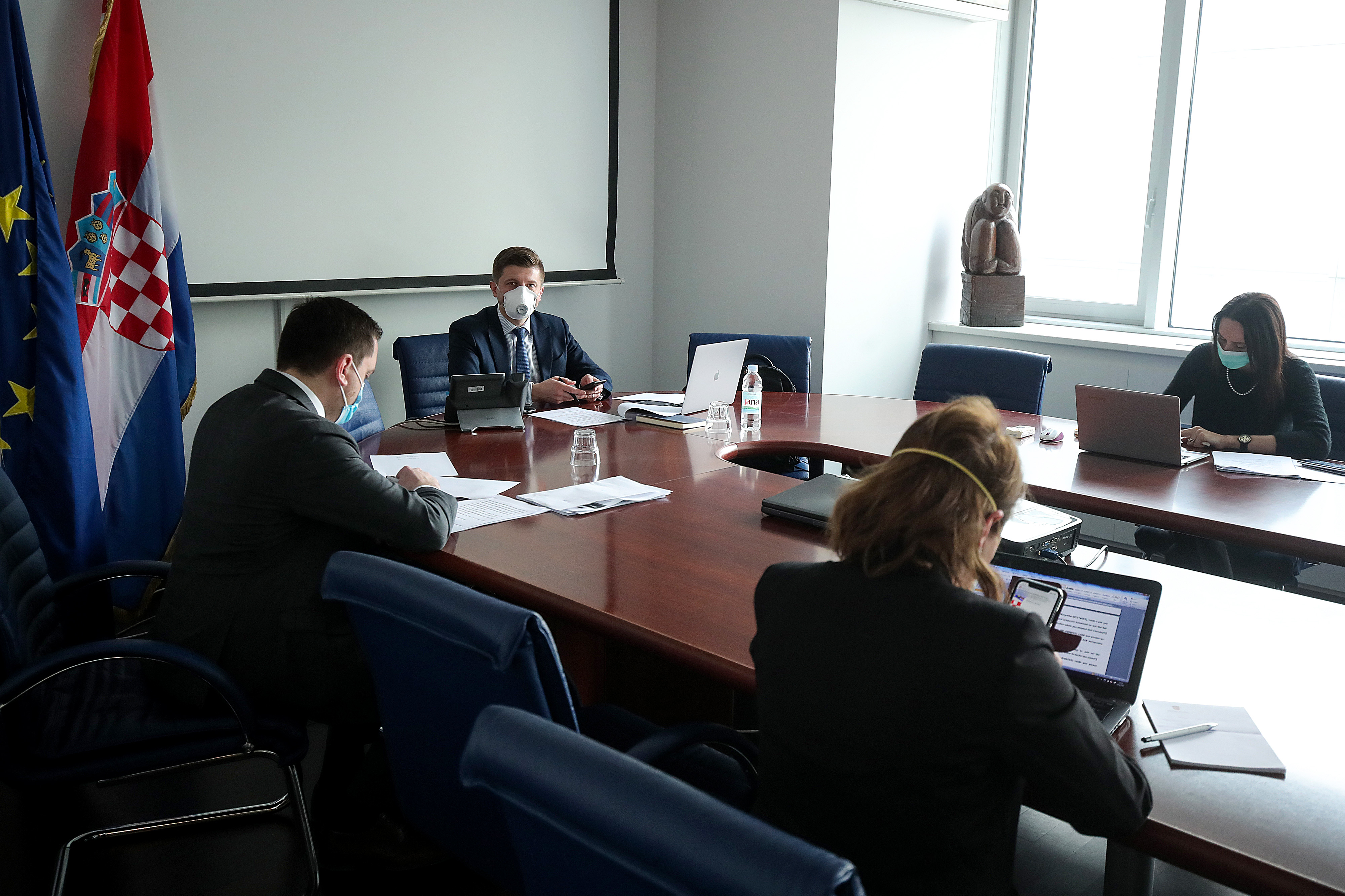 Los ministros de Economía y Hacienda sentados en la sala de teleconferencia y manteniendo la distancia social