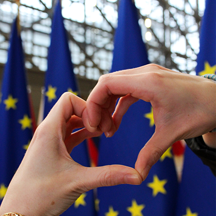 Palms forming a heart with EU flags in the background