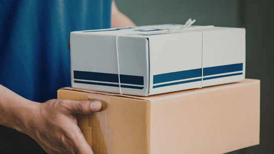 A person uses a handheld barcode scanner on a shelf of cardboard boxes in a warehouse, with stylised circuit lines in the background.